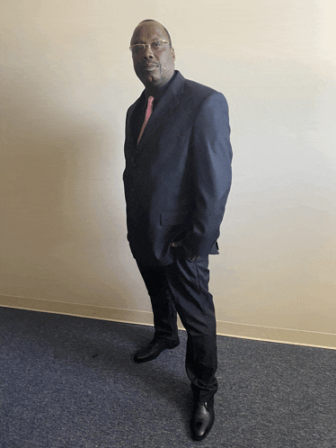 a man in a suit and tie standing with his hands in his pockets