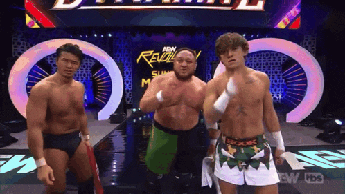 three wrestlers are standing on a stage in front of a revolution sign