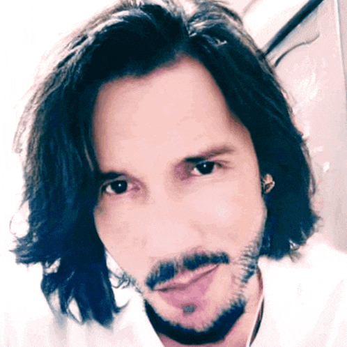 a man with long hair and a beard is smiling for the camera