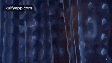 a close up of a person holding a sword in a room with a blue background .