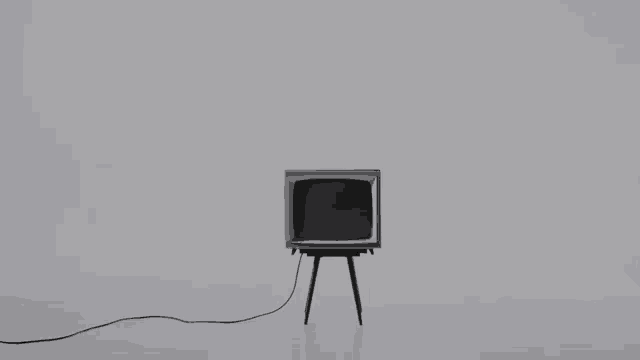 a man in a suit is walking towards a television with a gray screen