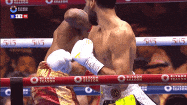 two boxers are fighting in a ring with a riyadh season advertisement on the ropes