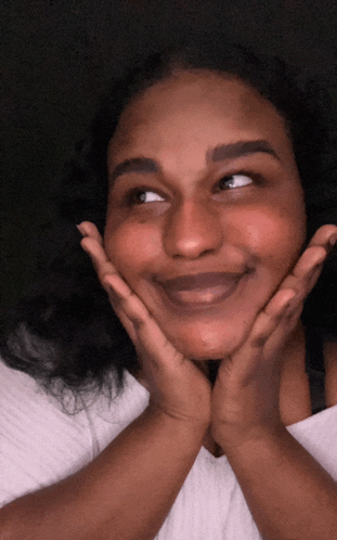 a woman with her hands on her face is smiling and looking up