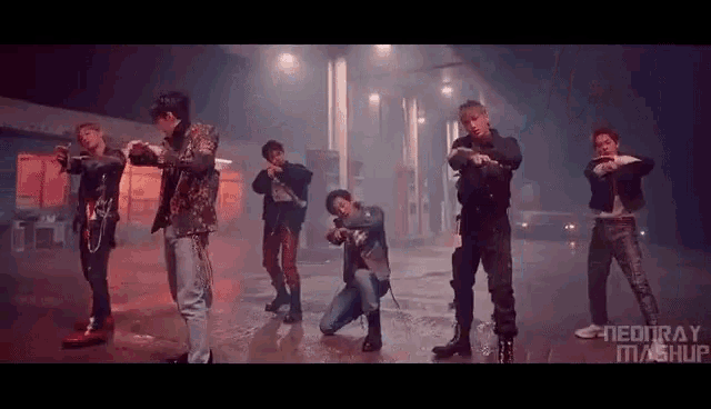 a group of men are standing next to each other in a dark room and dancing .