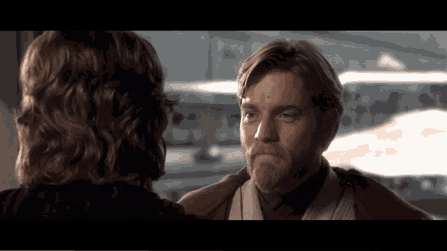 a man with a beard looks at another man with long hair