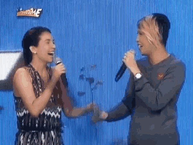 a man and a woman are singing into microphones while standing next to each other .