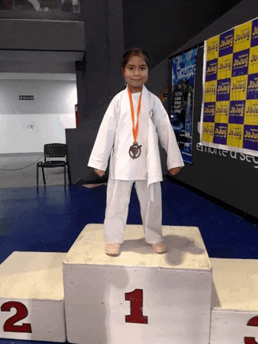 a young girl is standing on a podium with the number 1 on it