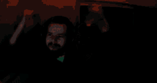 a man wearing headphones is dancing in a dark room with a green background