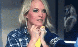 a woman wearing a plaid shirt and a yellow tie is looking at the camera