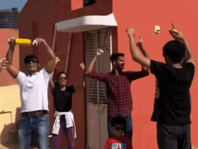 a group of people standing in front of a red building