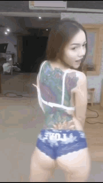 a woman with a tattoo on her back is standing in a room wearing shorts .