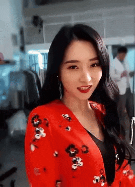 a woman in a red jacket with flowers on it is smiling and looking at the camera .