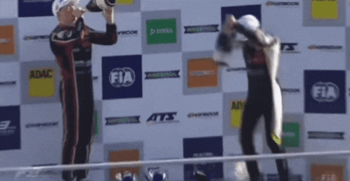 two men on a podium with fia logos on the wall