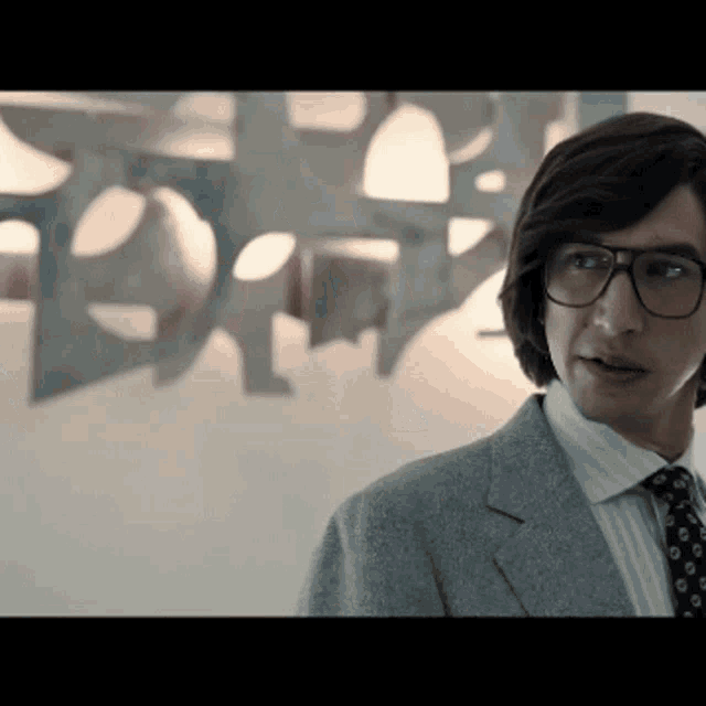 a man wearing glasses and a suit is standing in front of a sign that says ' ford '