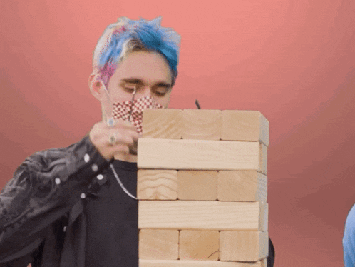 a man with blue hair stacking wooden blocks