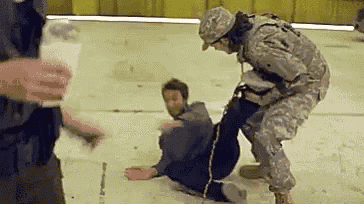 a soldier is kneeling down next to a man who is sitting on the floor .