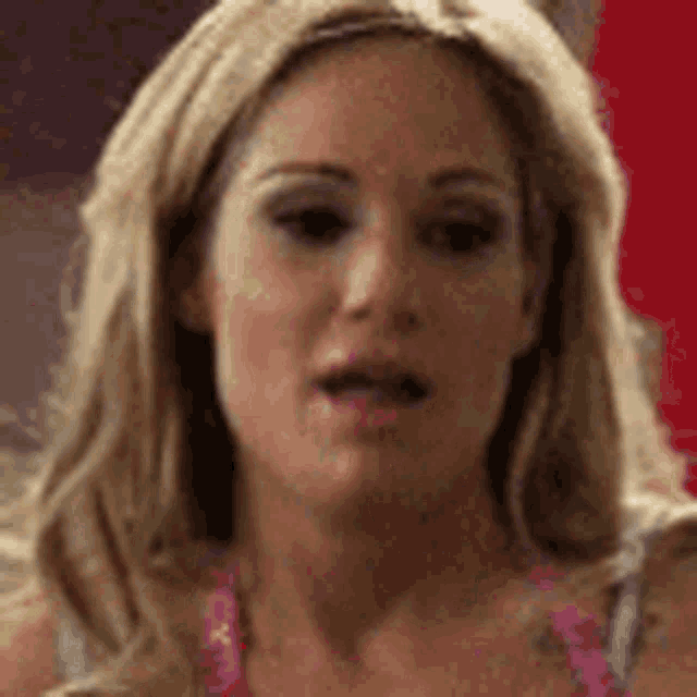 a close up of a woman 's face with her mouth open and a pink necklace .