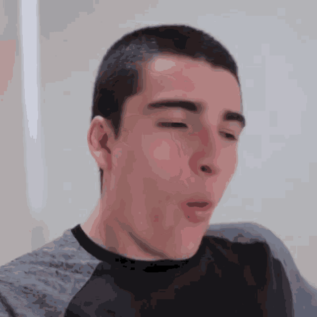 a young man with a shaved head is making a funny face .