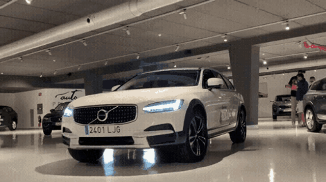 a white volvo with the license plate 2401 ljg is parked in a garage