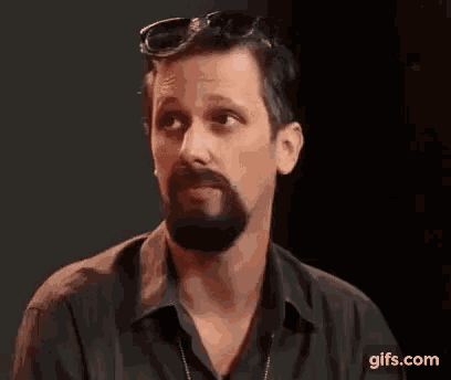 a man with a beard and sunglasses is making a face .