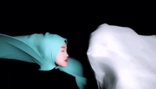 a woman wearing a green hijab and red lipstick