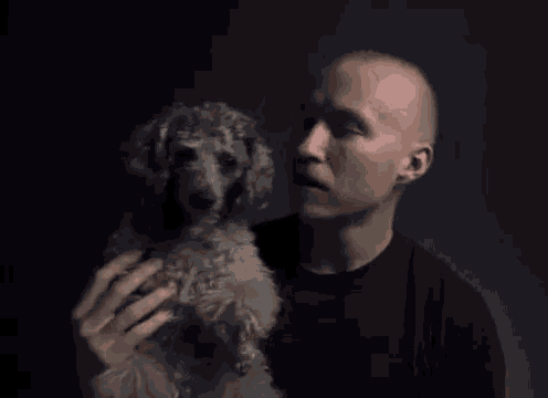 a man is kissing a small dog on the forehead .