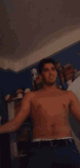 a shirtless man is standing in a kitchen
