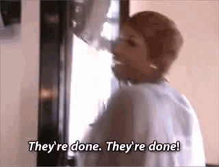 a woman is standing in front of a microwave and saying `` they 're done . they 're done . ''