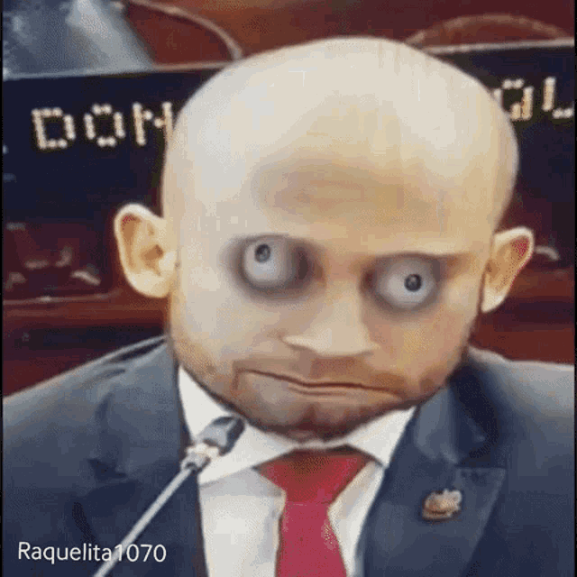 a bald man in a suit and tie is making a funny face .