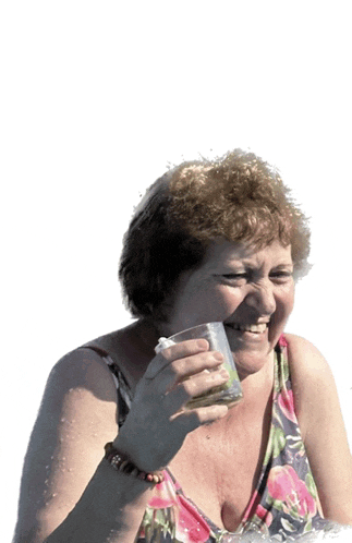 a woman in a floral top is holding a glass of water and smiling