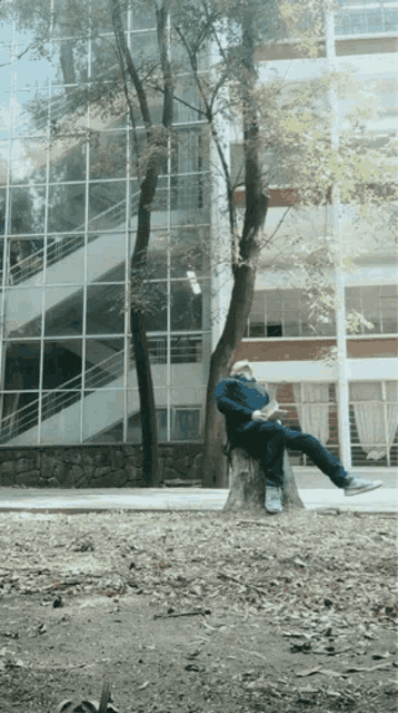 a man is sitting on a tree stump in front of a building