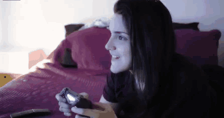 a woman laying on a bed holding a video game controller