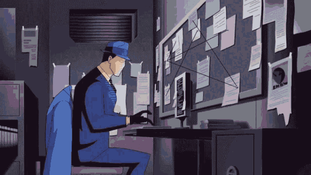 a man in a blue suit is sitting at a desk in front of a computer monitor