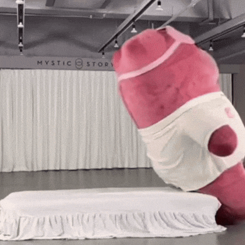 a pink stuffed animal is standing on a bed in front of a mystic story sign