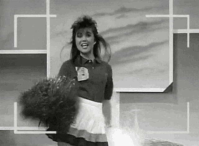 a cheerleader is holding a bunch of pom poms in her hands in a black and white photo .