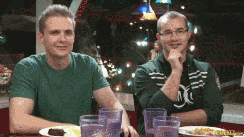 two men sitting at a table with plates of food and glasses of water