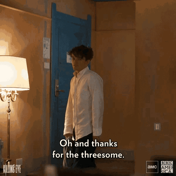 a man in a white shirt stands in front of a lamp and says oh and thanks for the threesome