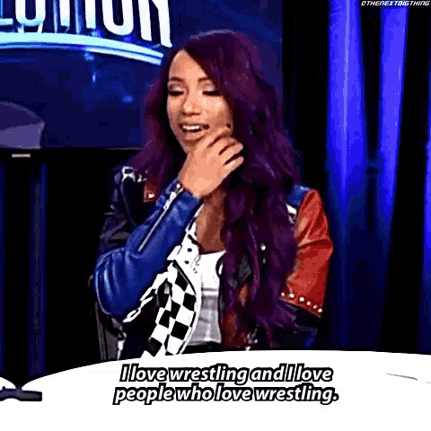 a woman with purple hair is sitting at a table and saying i love wrestling and i love people who love wrestling