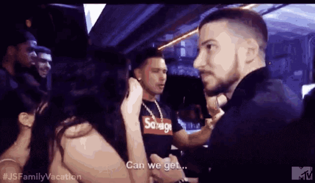 a man in a supreme shirt talks to a woman in a crowd