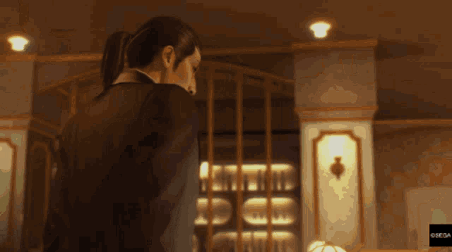 a man in a suit is standing in front of a shelf full of bottles with the word sega on the bottom