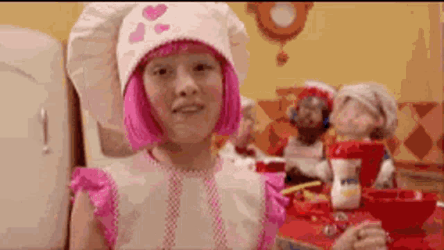 a little girl with pink hair is wearing a chef 's hat .