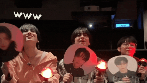 a group of people are holding fan sticks with their faces on them in front of a screen that says www .