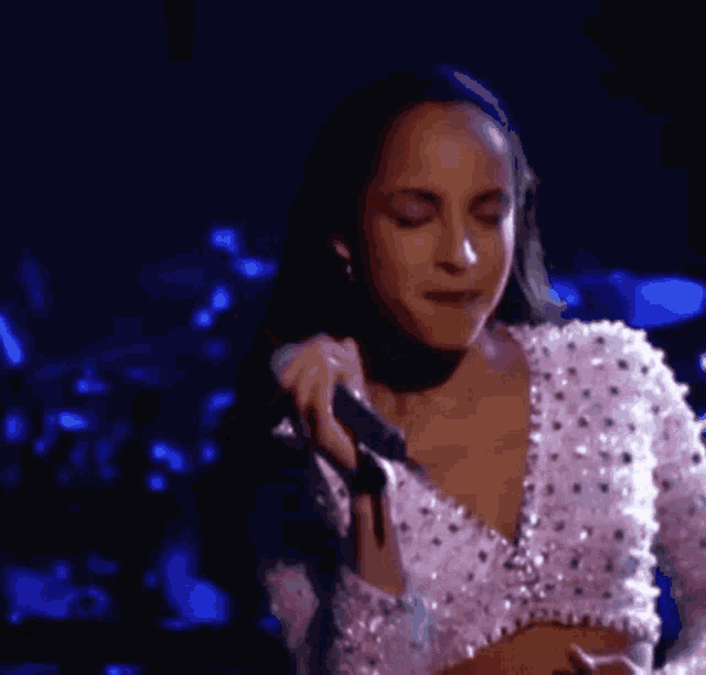a woman is singing into a microphone while wearing a crop top .