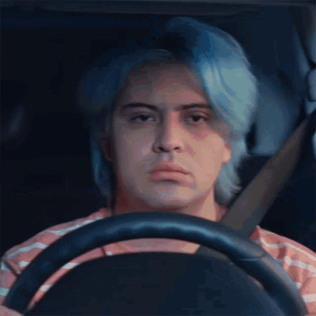 a man with blue hair is sitting in a car