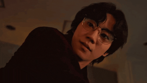 a man wearing glasses is looking at the camera and smiling .