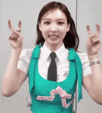 a woman in a green vest and tie is giving a peace sign