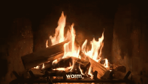 a fire is burning in a fireplace with the words warm written above it .