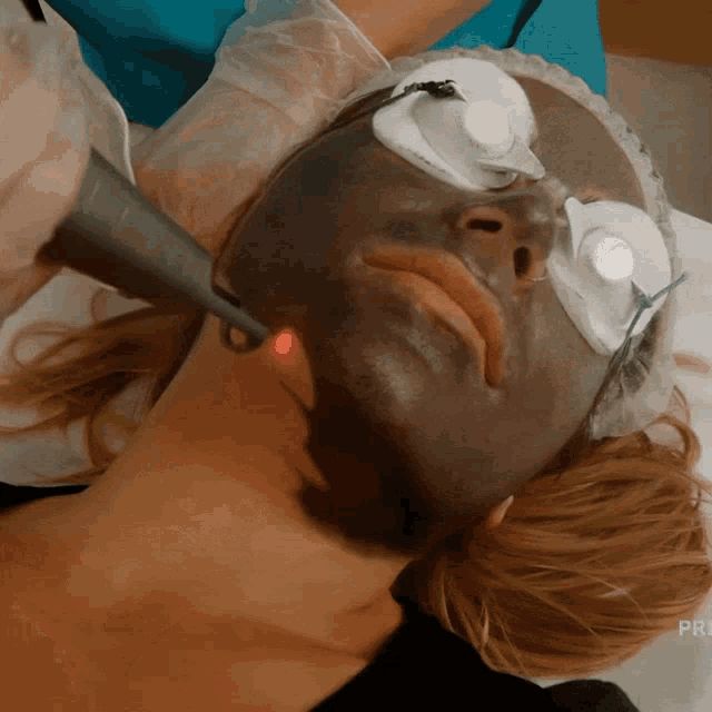 a woman with a black mask on her face is getting a facial treatment