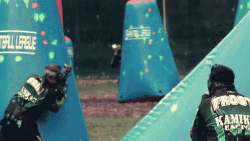 two paintball players are playing a game of paintball and one has frost on his back