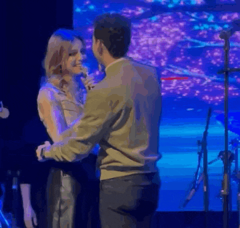 a man and woman are dancing on a stage in front of a microphone .